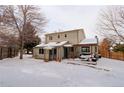 View of back exterior, showing a covered deck and fenced yard, all under a blanket of snow at 8012 S Cedar St, Littleton, CO 80120