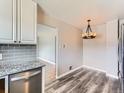 Stylish kitchenette with grey cabinets, a granite countertop, and a modern chandelier above a dining area at 10736 Logan Ct, Northglenn, CO 80233
