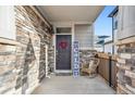 Cozy front porch with stone accents, featuring a decorated front door, rocking chair and welcoming signage at 765 N Shawnee St, Aurora, CO 80018