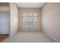 Bright, airy living room featuring neutral carpet, large windows with blinds, and a white front door at 11558 Pine Hill Way, Parker, CO 80138