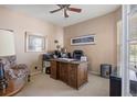 Cozy home office with a large, ornate wooden desk, a ceiling fan, and natural light from the window at 11558 Pine Hill Way, Parker, CO 80138