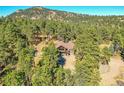 A stately home surrounded by mature trees with a stone facade and upper level deck at 24929 N Mountain Park Dr, Evergreen, CO 80439