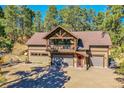 Stately home with stone facade and charming pink front door with outdoor seating at 24929 N Mountain Park Dr, Evergreen, CO 80439