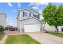 Two-story home with a two-car garage, a manicured lawn, and a mature tree in the front yard at 9625 Bighorn Way, Littleton, CO 80125