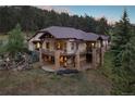Expansive home with a rustic design and spacious outdoor living area nestled in a wooded hillside at 22759 Mountain Spirit Way, Indian Hills, CO 80454