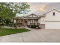 Charming home with covered porch, stone accents, mature trees, and manicured landscaping at 8211 E 128Th Pl, Thornton, CO 80602