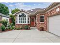 Front exterior showcasing brick facade, concrete driveway, and meticulously maintained landscaping including flower gardens and shrubs at 3413 Boxelder Dr, Longmont, CO 80503