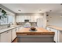 Well-lit kitchen showcasing white cabinetry, butcher block island, and modern fixtures at 6492 Simms St # A, Arvada, CO 80004