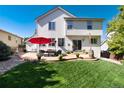 A spacious backyard with a concrete patio, outdoor seating, and a lush green lawn at 2880 Breezy Ln, Castle Rock, CO 80109