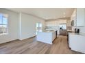 Modern kitchen with stainless steel appliances, white cabinets, an island with sink, and lots of natural light at 720 N Deer Park St, Watkins, CO 80137