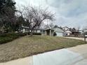 View of a one-story home featuring a lush, green lawn, mature trees, and a two-car garage at 16180 E Flora Pl, Aurora, CO 80013