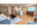 Open-concept living and dining area with hardwood floors and modern lighting fixtures at 6484 S Datura St, Littleton, CO 80120