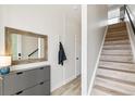 A clean entryway with light wood floors, a gray storage cabinet, a modern mirror, and a staircase at 5367 W 14Th Ave, Lakewood, CO 80214