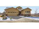 Charming tan house with well-kept landscaping, stone accents, and a concrete driveway with snow at 2600 Reserve Ct, Erie, CO 80516