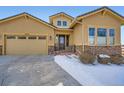 Charming tan house with well-kept landscaping, stone accents, and a concrete driveway with snow at 2600 Reserve Ct, Erie, CO 80516