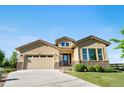 Beautifully landscaped tan home featuring a two-car garage, stone accents, and a well-maintained lawn at 2600 Reserve Ct, Erie, CO 80516