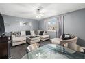 Comfortable living room featuring a sectional sofa, a decorative glass table, and a window with curtains at 2562 E 90Th Pl, Thornton, CO 80229