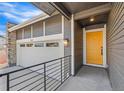 Home exterior with a yellow front door, stone accents, and two-car garage at 9283 Biscay St, Commerce City, CO 80022