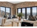 Inviting living room with brick accent wall, modern furniture, and scenic views from expansive windows and walk out deck at 1140 Lake Gulch Rd, Castle Rock, CO 80104