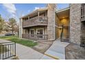 The exterior of the condominium displays a stone chimney and multiple walkways for easy access at 3400 S Eagle St # 104, Aurora, CO 80014