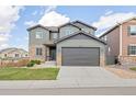 Charming two-story home with a gray exterior, stone accents, manicured lawn, and a two-car garage at 880 Mcmurdo Cir, Castle Rock, CO 80108