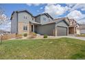 Charming two-story home with a gray exterior, stone accents, manicured lawn, and a two-car garage at 880 Mcmurdo Cir, Castle Rock, CO 80108