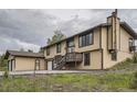 Charming two-story home with tan siding, a chimney, large windows and an attached two-car garage at 30839 Manitoba Dr, Evergreen, CO 80439