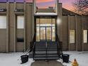 The Morningside Clubhouse entry features glass doors and snow-covered stairs in front of a beige brick facade at 6930 E Girard Ave # 304, Denver, CO 80224