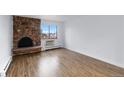 Bright living room featuring hardwood floors, a cozy brick fireplace, and a large window with city views at 1008 N Corona St # 405, Denver, CO 80218