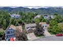 Aerial view of a two-story brown house nestled among trees with mountain views in the background at 573 Entrada Dr, Golden, CO 80401