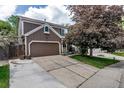 A two-story brown home has an attached two-car garage with a driveway leading to a cozy front porch at 573 Entrada Dr, Golden, CO 80401