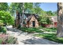 Brick home with driveway and mature trees, offering a welcoming and established setting at 1661 Oneida St, Denver, CO 80220