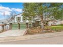 Inviting two-story home with a three-car garage, manicured lawn, and mature trees creating curb appeal at 7681 S Jellison St, Littleton, CO 80127