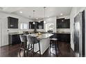 Modern kitchen featuring dark cabinets, granite countertops, and a center island with seating at 20888 E 51St Pl, Denver, CO 80249
