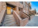 Inviting brick townhome entrance with stairs leading to a bright yellow front door and well-maintained landscaping at 2706 Blake St, Denver, CO 80205