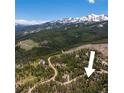 Aerial view of a wooded area with snowy mountain peaks in the background, showing the property's location at 91 Slalom Dr, Breckenridge, CO 80424
