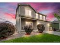 Charming two-story home with landscaped front yard, gravel beds, and attached two-car garage at sunset at 7218 Animas Ave, Frederick, CO 80530
