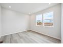 Bright bedroom with light gray wood floors, recessed lighting, and large windows providing ample light at 1263 Rhett Dr, Erie, CO 80026