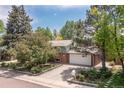 Charming two-story home surrounded by mature trees and landscaping, featuring a brick facade and two-car garage at 7046 W 62Nd Pl, Arvada, CO 80003