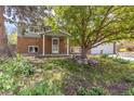 Two-story home with beautiful yard, mature trees, and a partial brick facade, complete with a two-car garage at 7046 W 62Nd Pl, Arvada, CO 80003