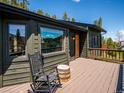 Outdoor deck featuring a rocking chair, wooden barrel table, and a scenic view of the surrounding landscape at 34075 Grouse Ln, Evergreen, CO 80439