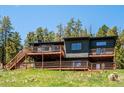 Exterior shot of beautiful multi-level home featuring a large wooden deck and mature trees at 34075 Grouse Ln, Evergreen, CO 80439