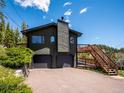 Front exterior view of a home featuring an attached two-car garage and multiple decks with access stairs at 34075 Grouse Ln, Evergreen, CO 80439