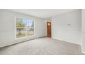 Bright living room featuring gray carpet, large window, and a wooden front door at 16835 E Harvard Pl, Aurora, CO 80013