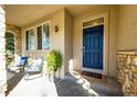 Cozy covered porch with stone accents, comfortable seating, and a bright blue front door at 4968 Montvale Dr, Highlands Ranch, CO 80130