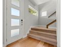 Bright entryway featuring hardwood floors, a modern door with glass panels and carpeted stairs at 5988 N Boston St, Denver, CO 80238