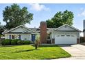 Well-maintained single-Gathering home featuring a two-car garage, a red brick chimney, and lush green lawn at 5193 S Flanders Ln, Centennial, CO 80015