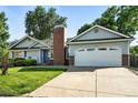 Charming home showcasing a two-car garage and lush lawn, enhanced by a prominent brick chimney at 5193 S Flanders Ln, Centennial, CO 80015