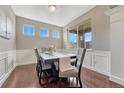 Formal dining room featuring wainscotting, hardwood floors, large windows, and a stylish table setting at 19382 Dunraven St, Parker, CO 80134
