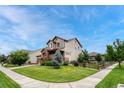 Two-story home with well-maintained lawn, garden beds, mature trees, and fenced yard on a corner lot at 19382 Dunraven St, Parker, CO 80134